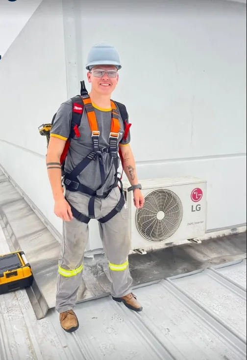 Técnico da Galvantech com equipamento de segurança ao lado da unidade externa de um ar-condicionado